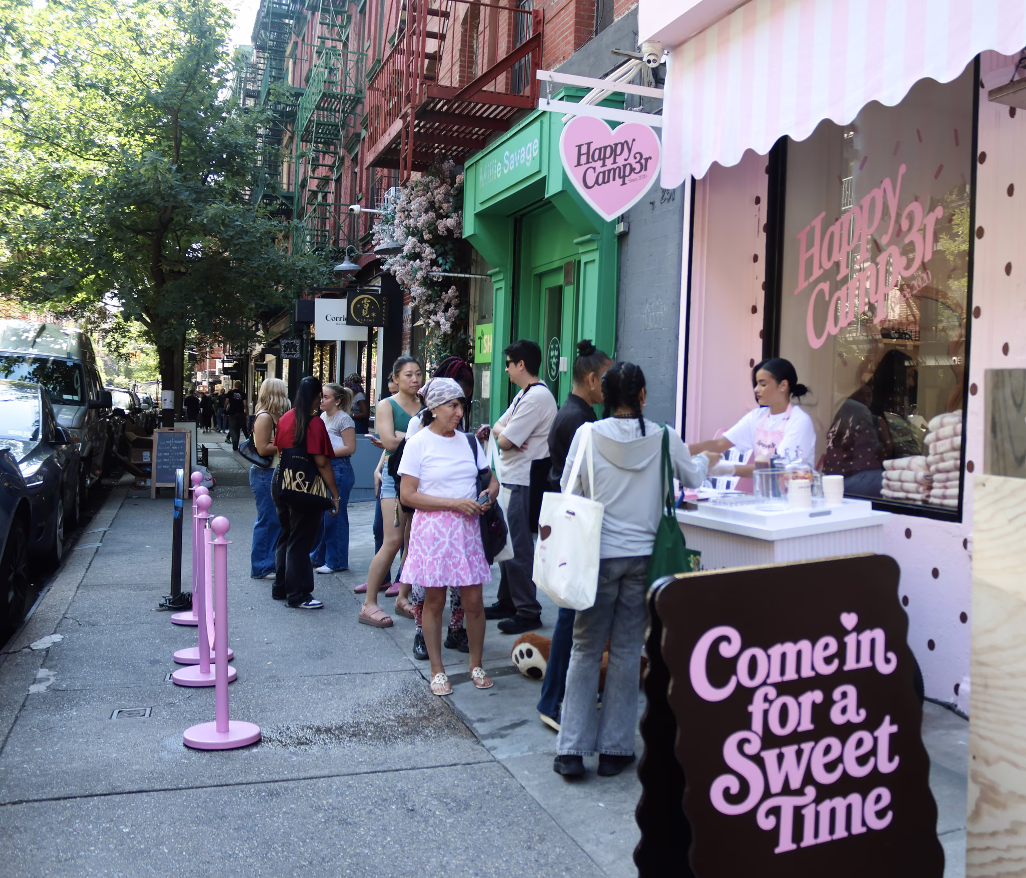 A queue of people down Elizabeth Street outside the pink Happy Camp3r pop-up in Nolita